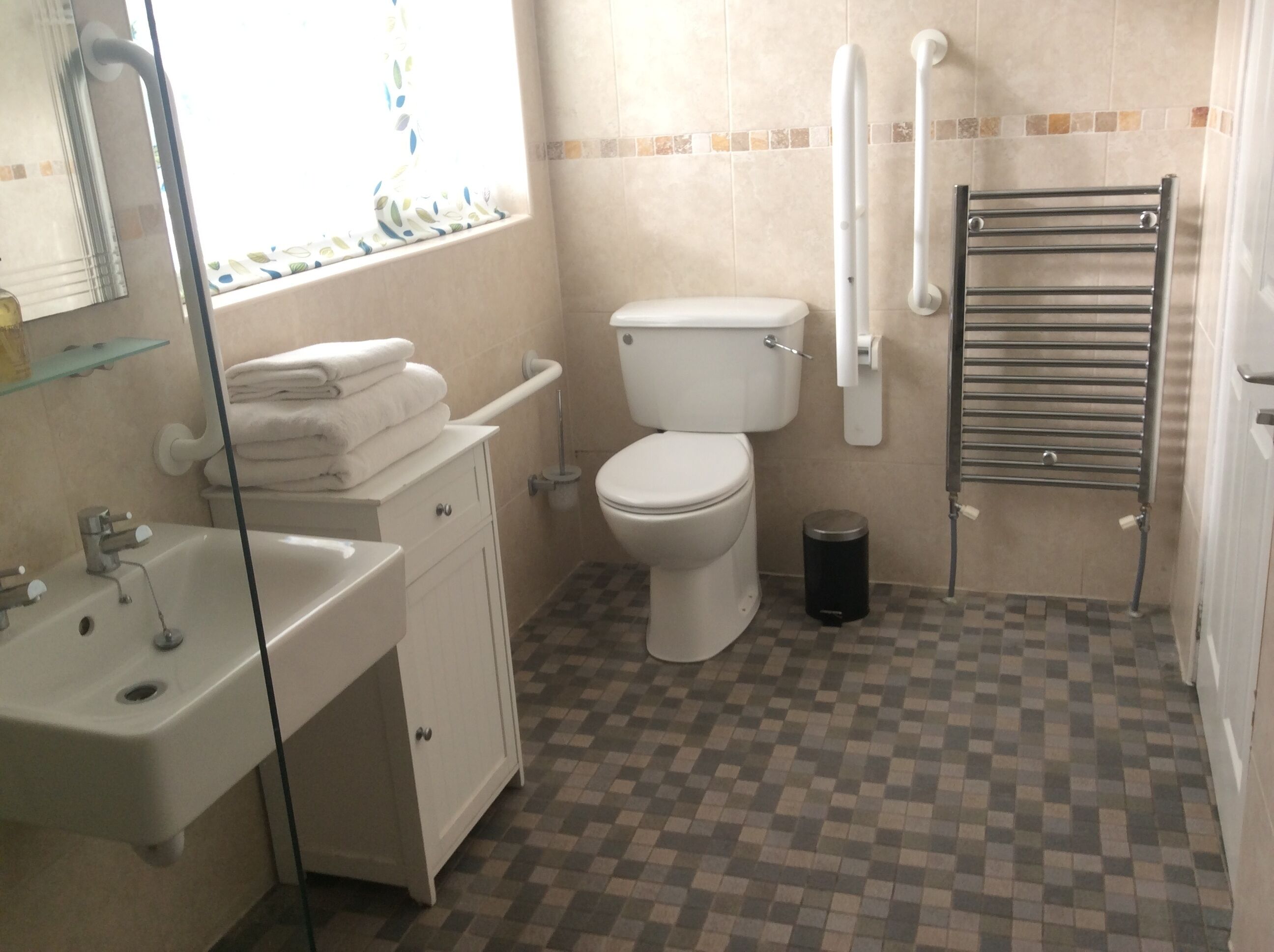 A bathroom with a toilet, sink, and bathtub. There is a towel rack and a trash can.