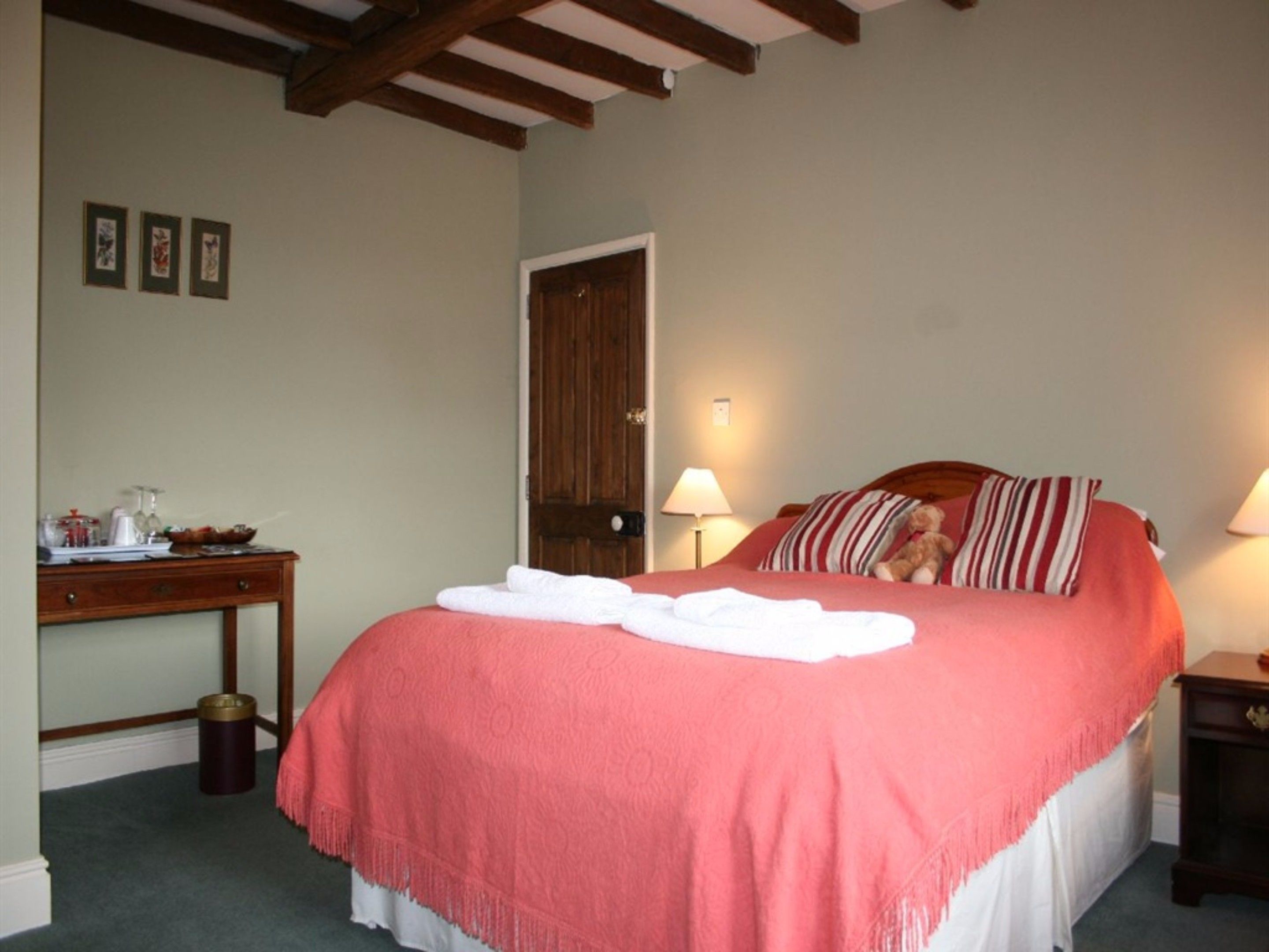 A bedroom with a bed, a bedside table, a lamp, and a door.