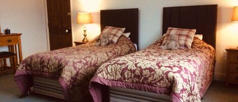 A double bed with floral bedding and two nightstands with lamps.