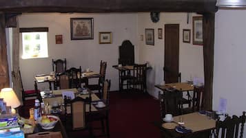 A dining area with wooden furniture, a red carpet, and framed pictures on the walls.