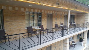 A balcony with outdoor seating, a brick building, and a window with the number 27. - The Happy Hollow (Hot Springs)