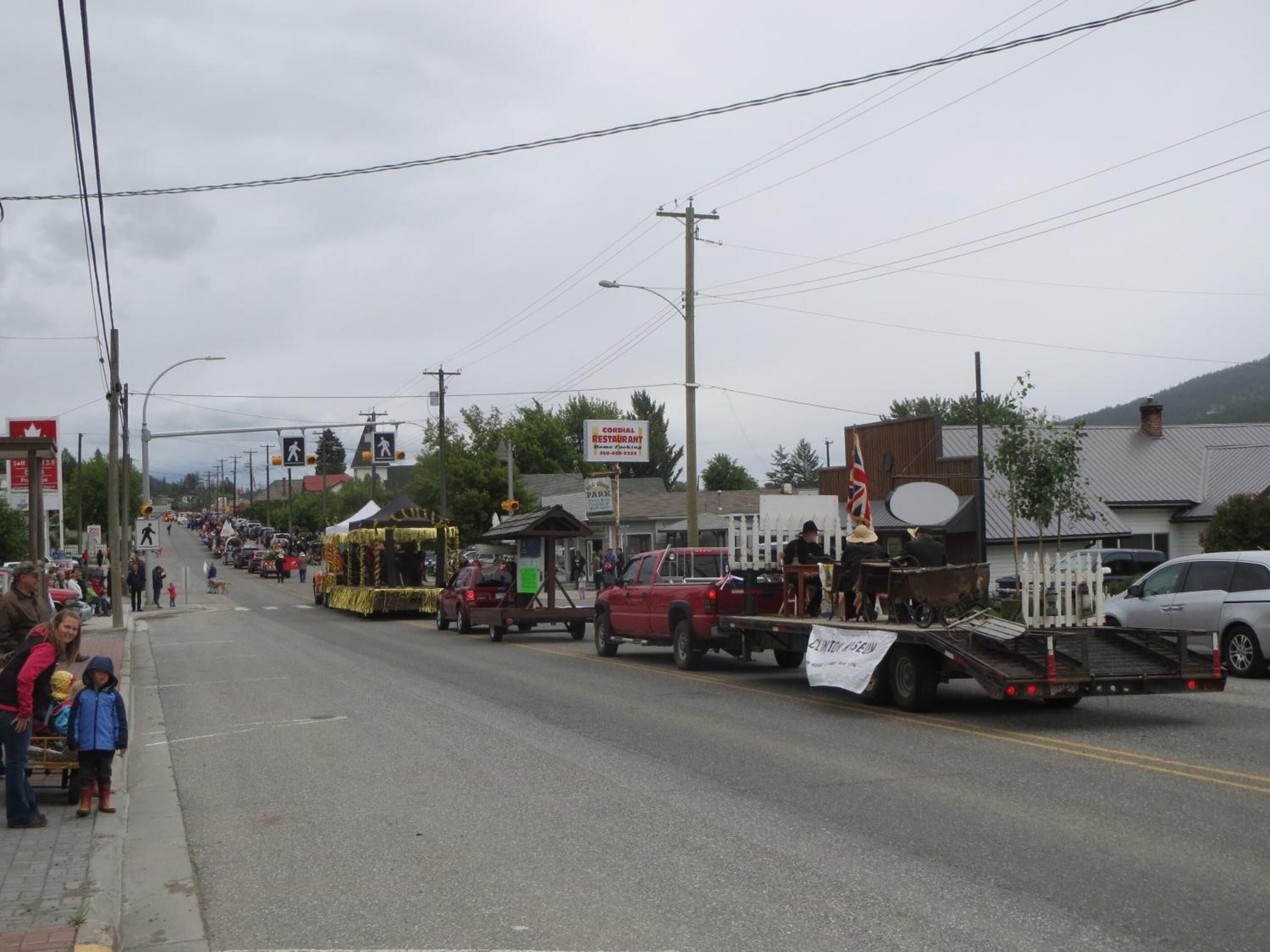 A street scene with a parade float, buildings, and a gas station sign.