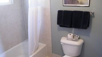 A bathroom with a bathtub, toilet, and a framed picture on the wall.