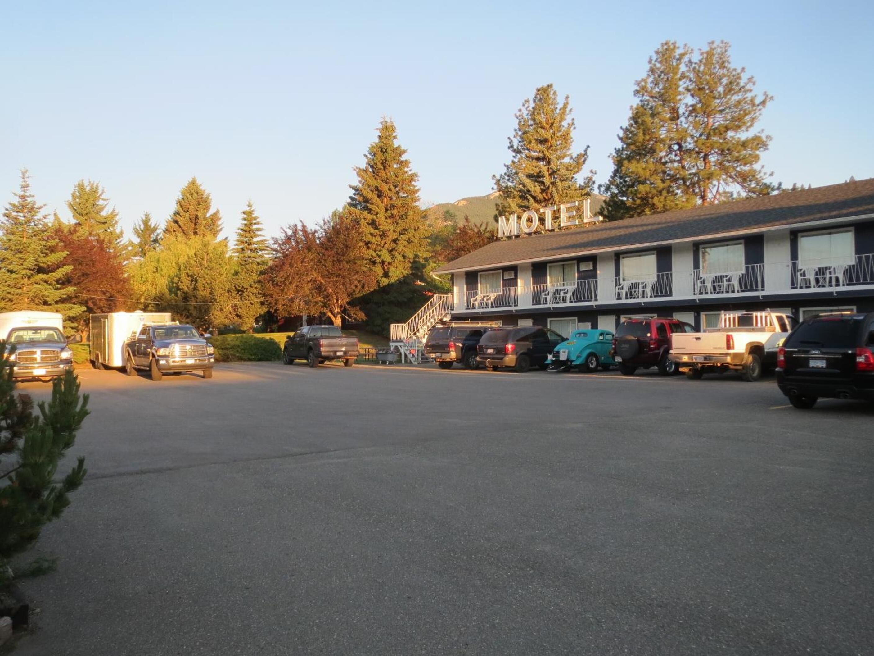 Un motel composé d’un bâtiment à deux étages, d’un parking et entouré d’arbres.