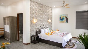 A modern bedroom with a large bed, a ceiling fan, and a wall-mounted light fixture. - J&R Residence (Anda)