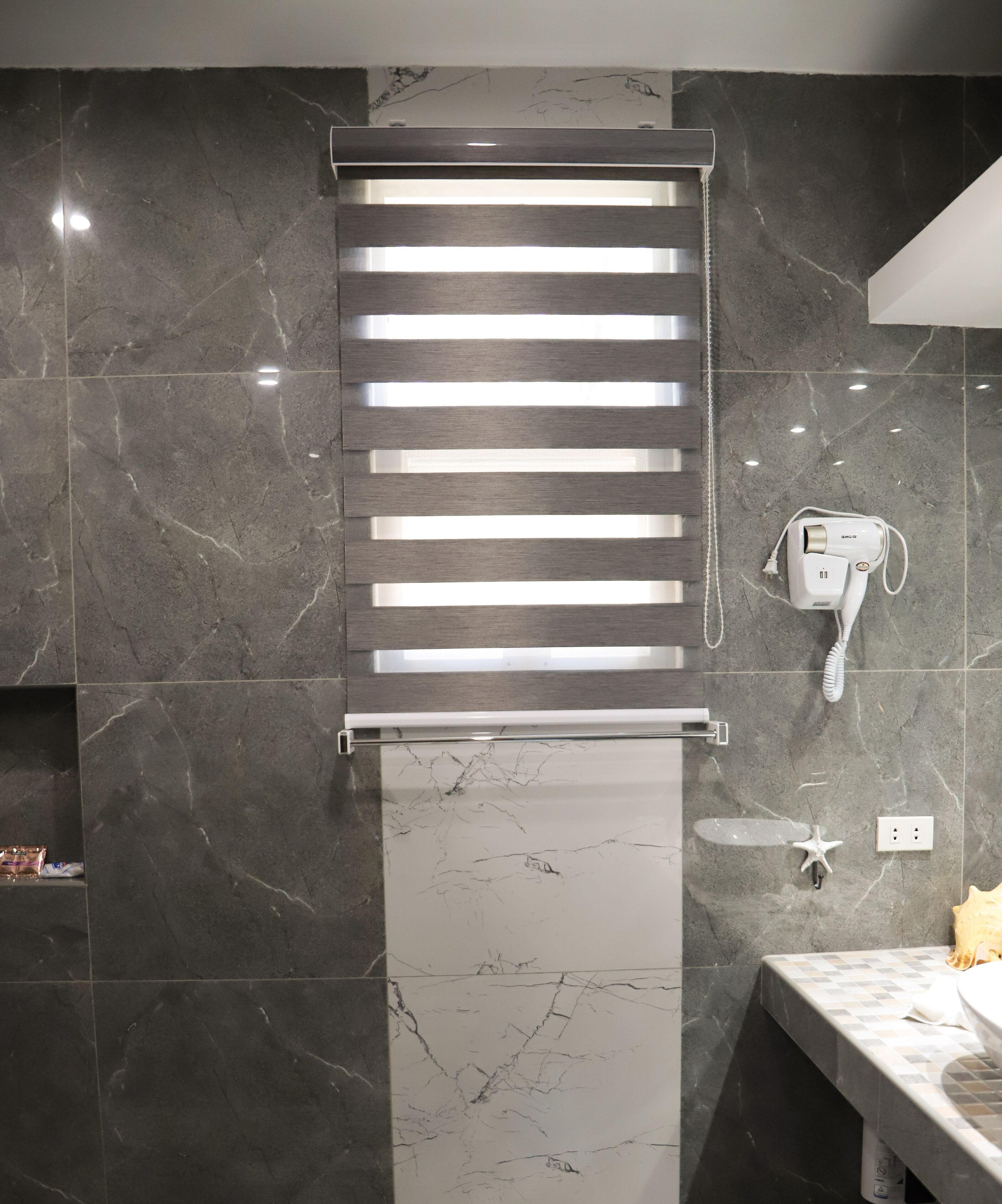 A bathroom with a towel rack, a hairdryer, and a starfish decoration on the wall.