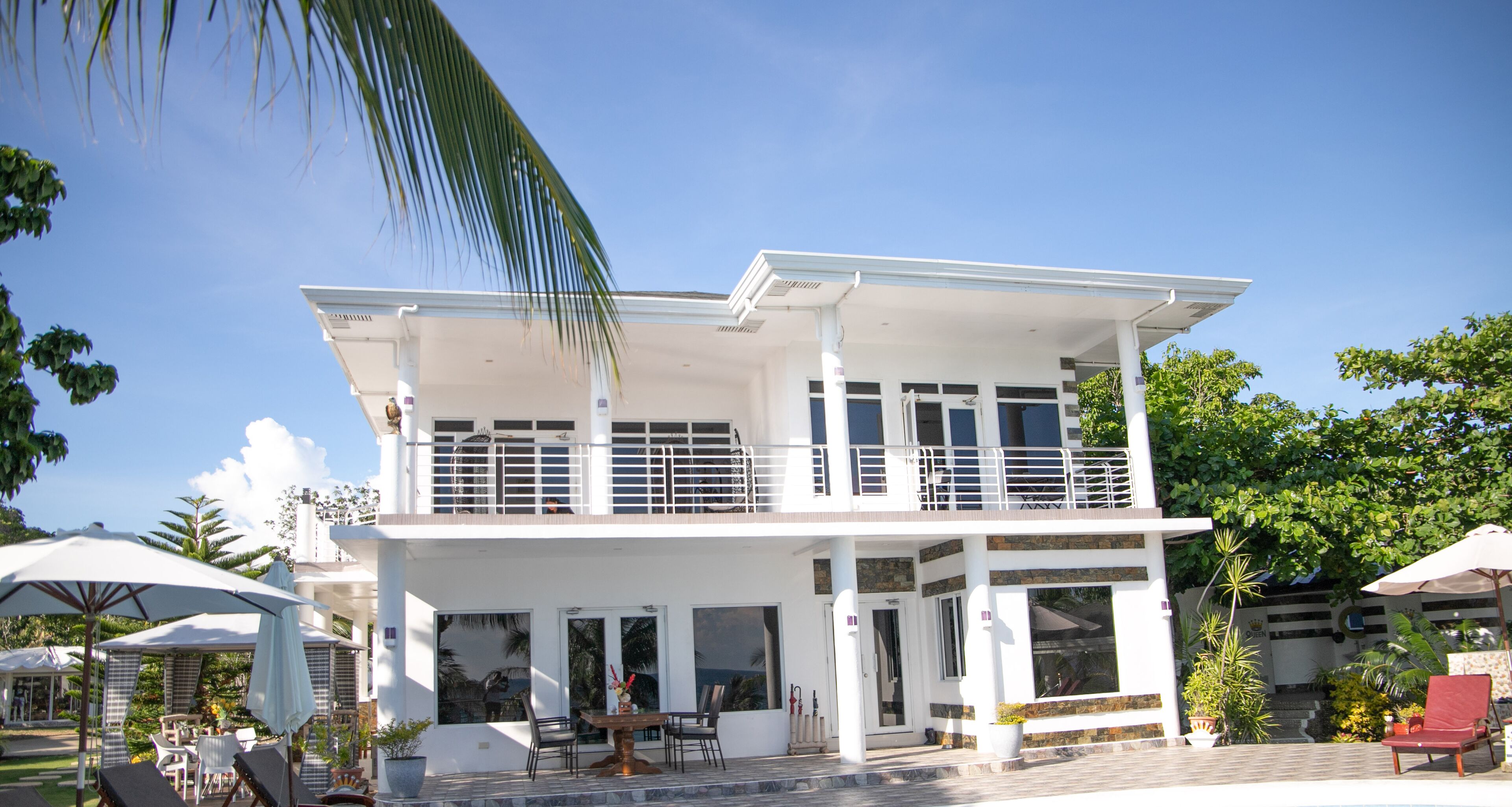 A two-story building with a balcony, outdoor seating, and a pool area.