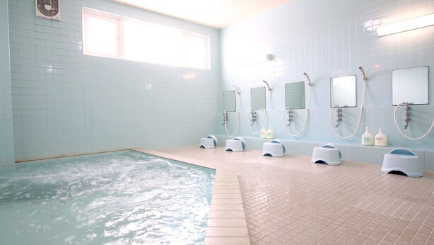 Un baño con una bañera grande, varios cabezales de ducha y una ventana.