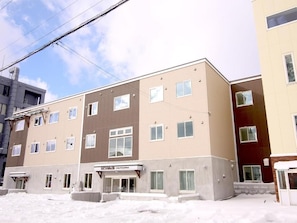 A multi-story hotel with a flat facade, multiple windows, and a visible entrance. - Lodge Koropokkuru (Kutchan)
