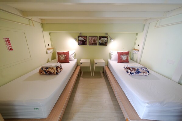 Una habitación con dos camas individuales, una mesita pequeña y lámparas de pared.