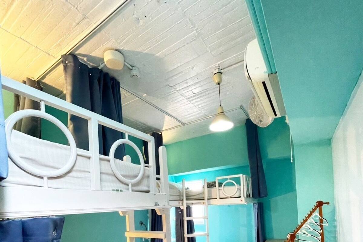 Une chambre avec un lit superposé, une échelle, une petite table et une chaise.