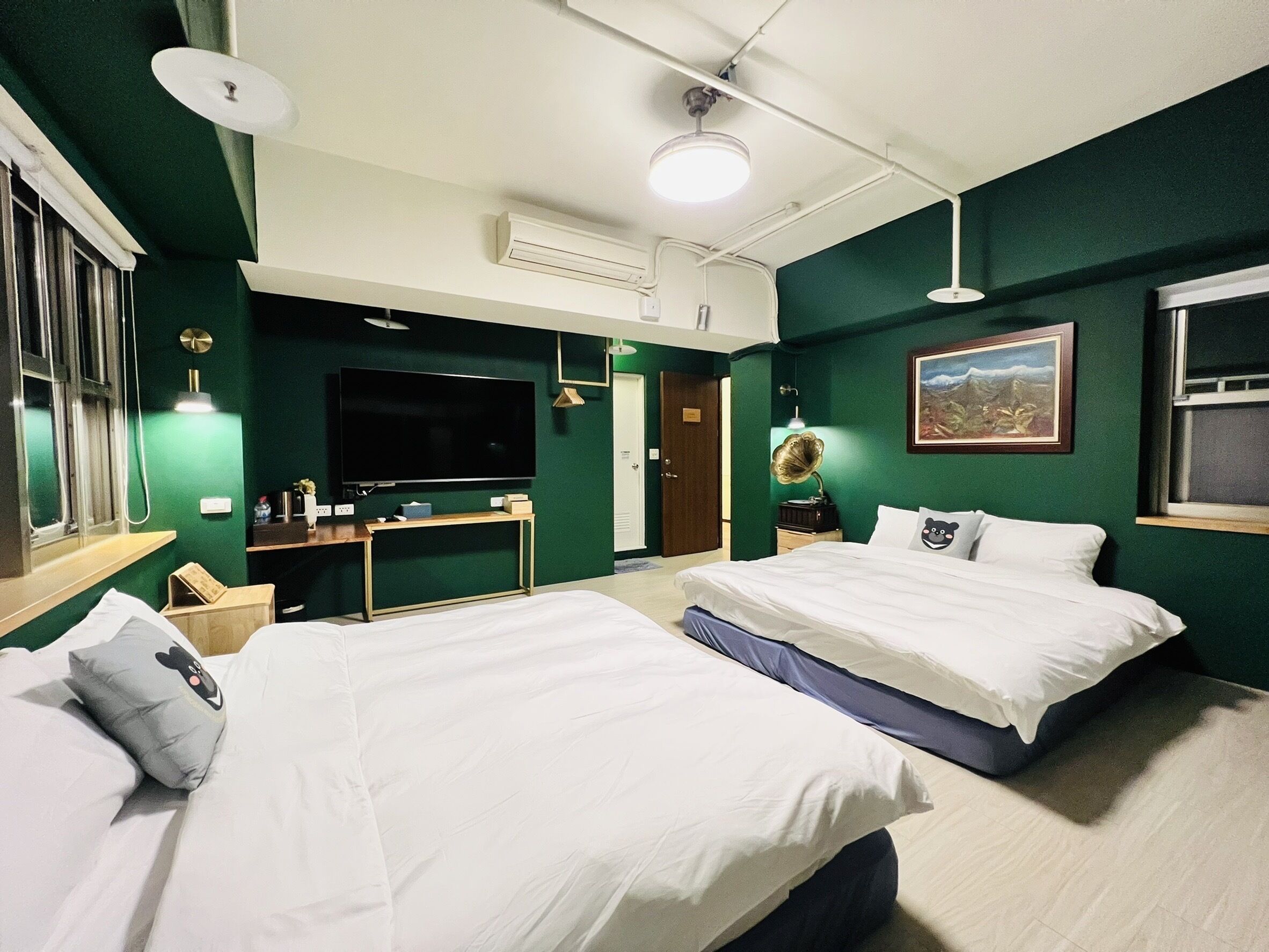 A hotel room with two beds, a TV, a desk, and a painting on the wall.