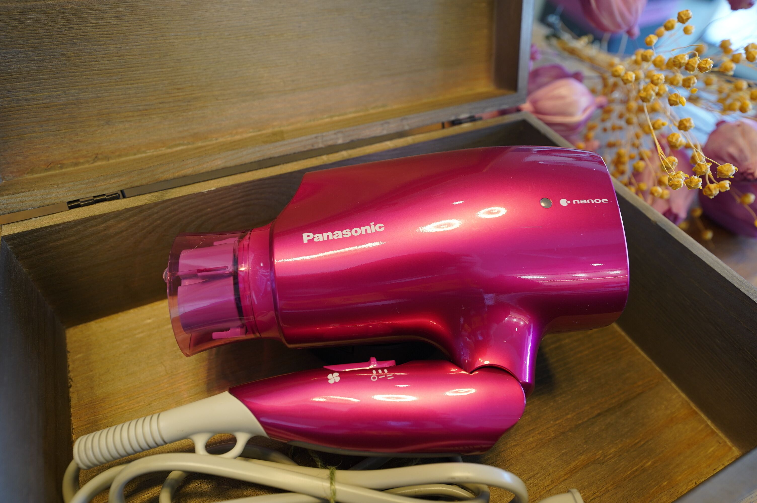 A pink Panasonic hair dryer in a wooden drawer.
