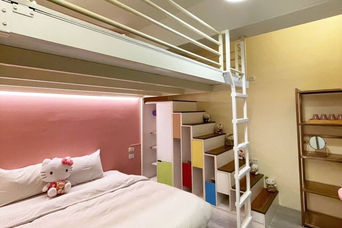 Une chambre avec un lit superposé, une échelle, un lit orné d’un coussin à l’effigie de Hello Kitty et une étagère avec des figurines de Hello Kitty.