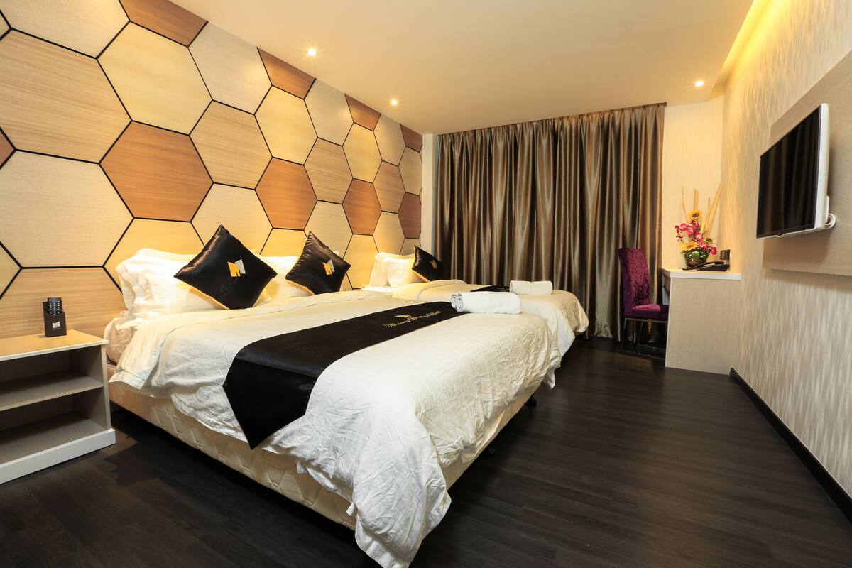 Une chambre d’hôtel moderne avec un grand lit, un bureau et un téléviseur fixé au mur.