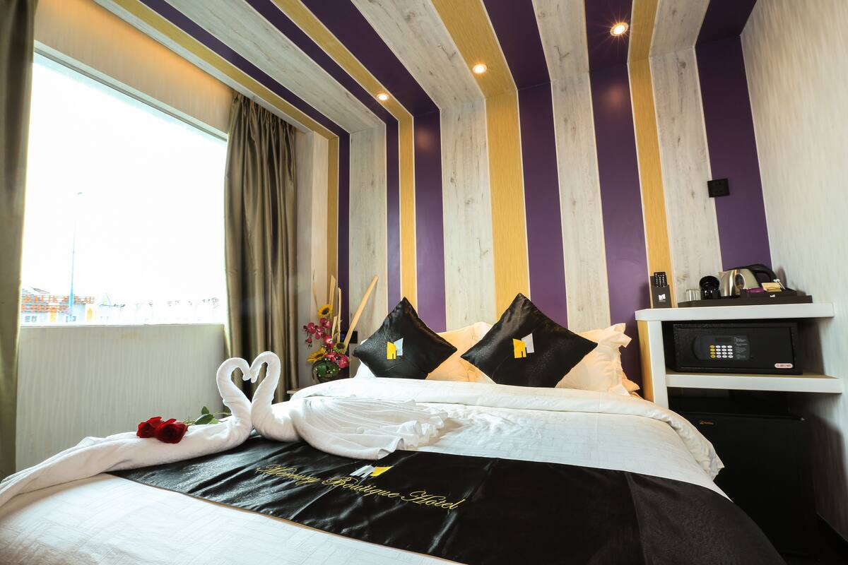 Une chambre d’hôtel avec un lit, une table de chevet, un four à micro-ondes et une fenêtre avec des rideaux.