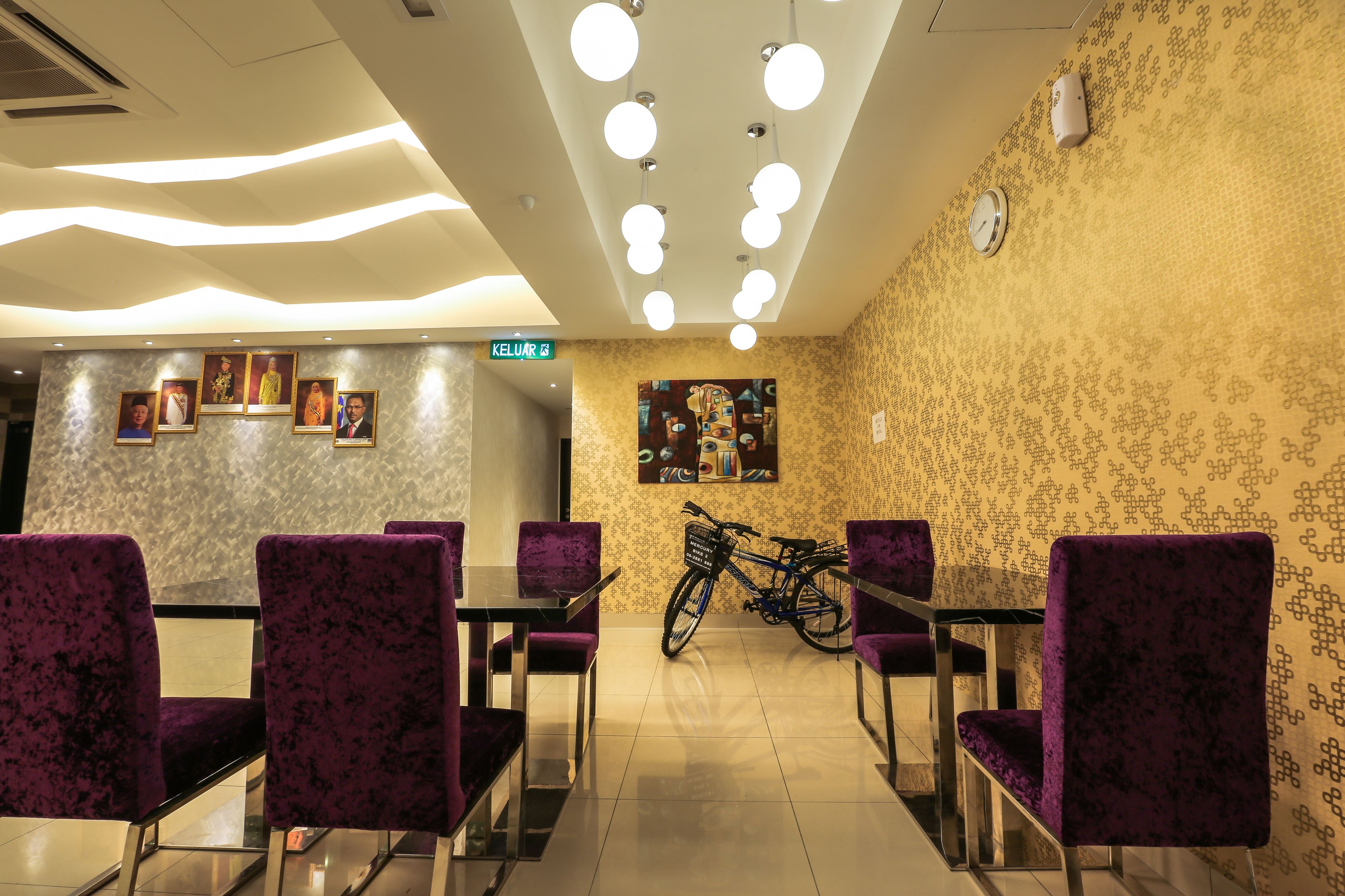 A dining area with purple upholstered chairs and tables, a bicycle, and a wall with patterned wallpaper and framed pictures.