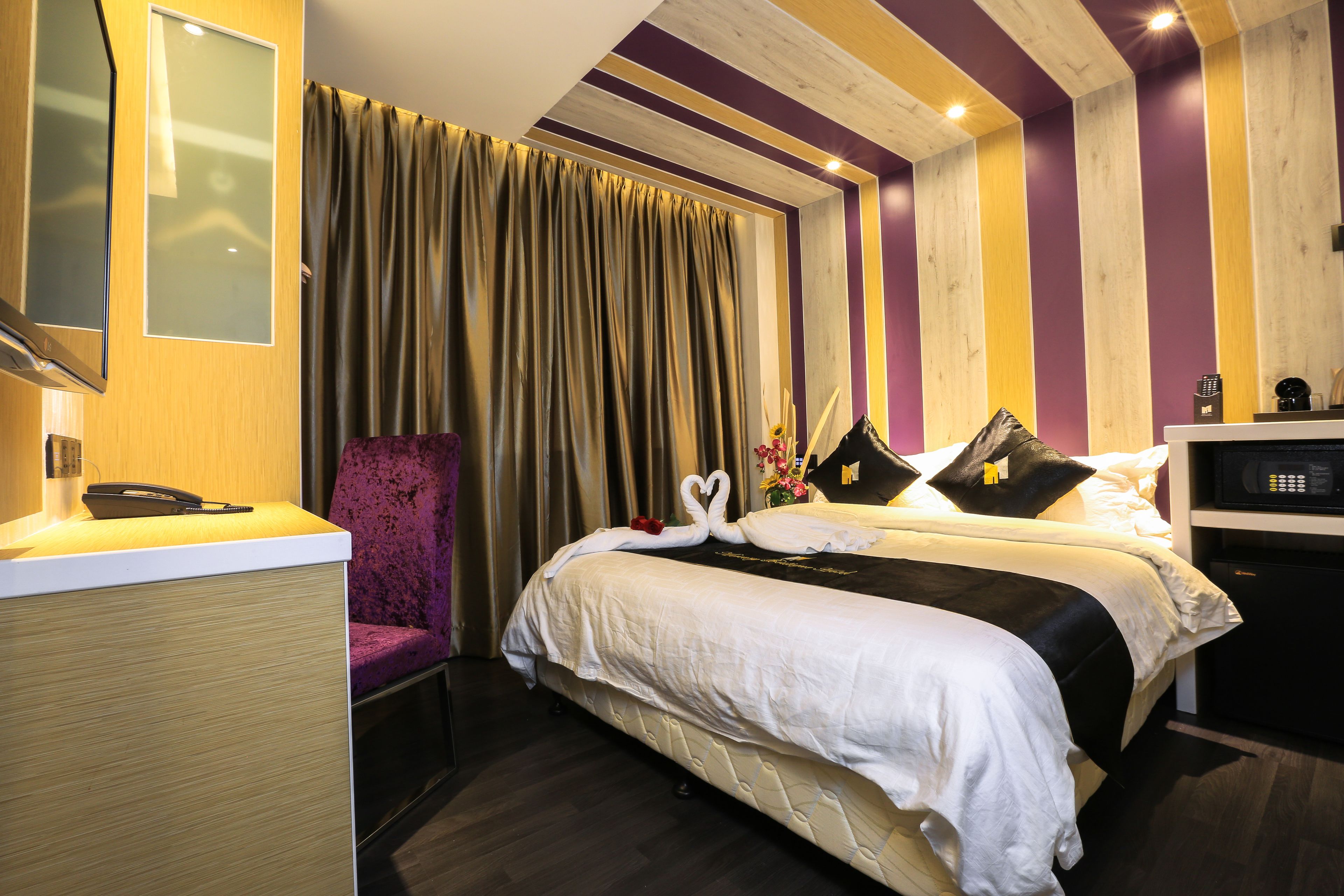 A hotel room with a bed, a desk, a chair, and a curtain.