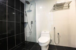 A modern bathroom with black and white tiles, a white toilet, a shower with a handheld showerhead, and a towel rack.