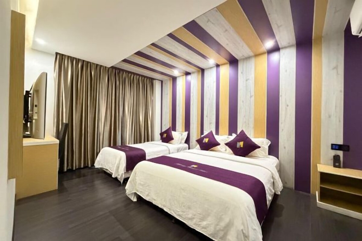 A hotel room with two beds, a wooden ceiling, and a curtain.