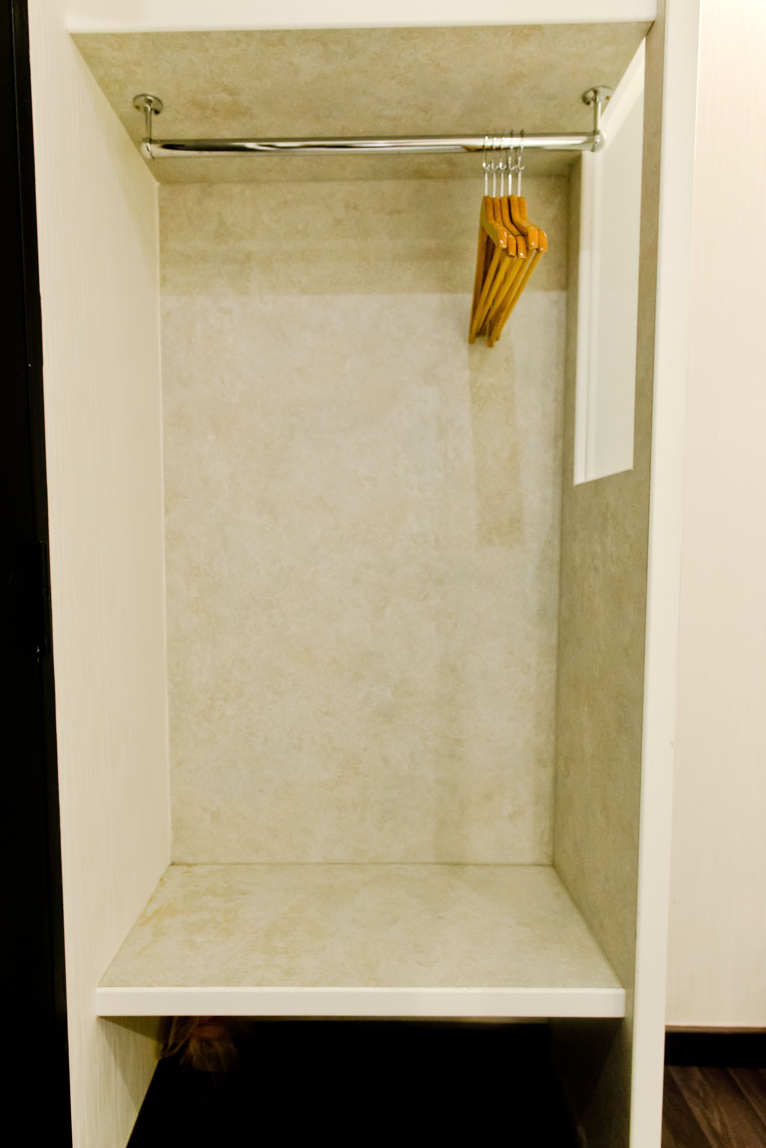 Une salle de bain avec un mur recouvert de carreaux beiges, une étagère blanche et un porte-serviettes en bois avec des serviettes.