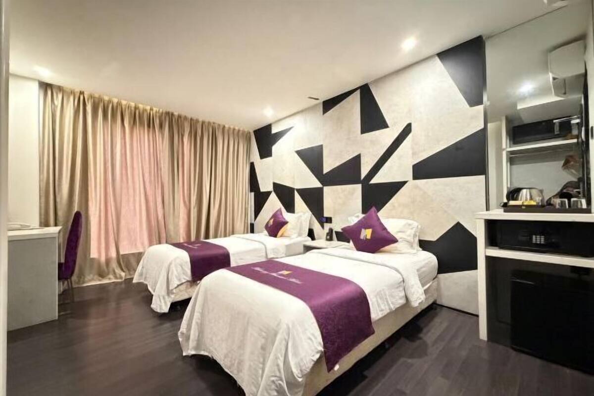 Une chambre d’hôtel avec deux lits, un bureau, une chaise, un mini-bar et une grande fenêtre avec des rideaux.