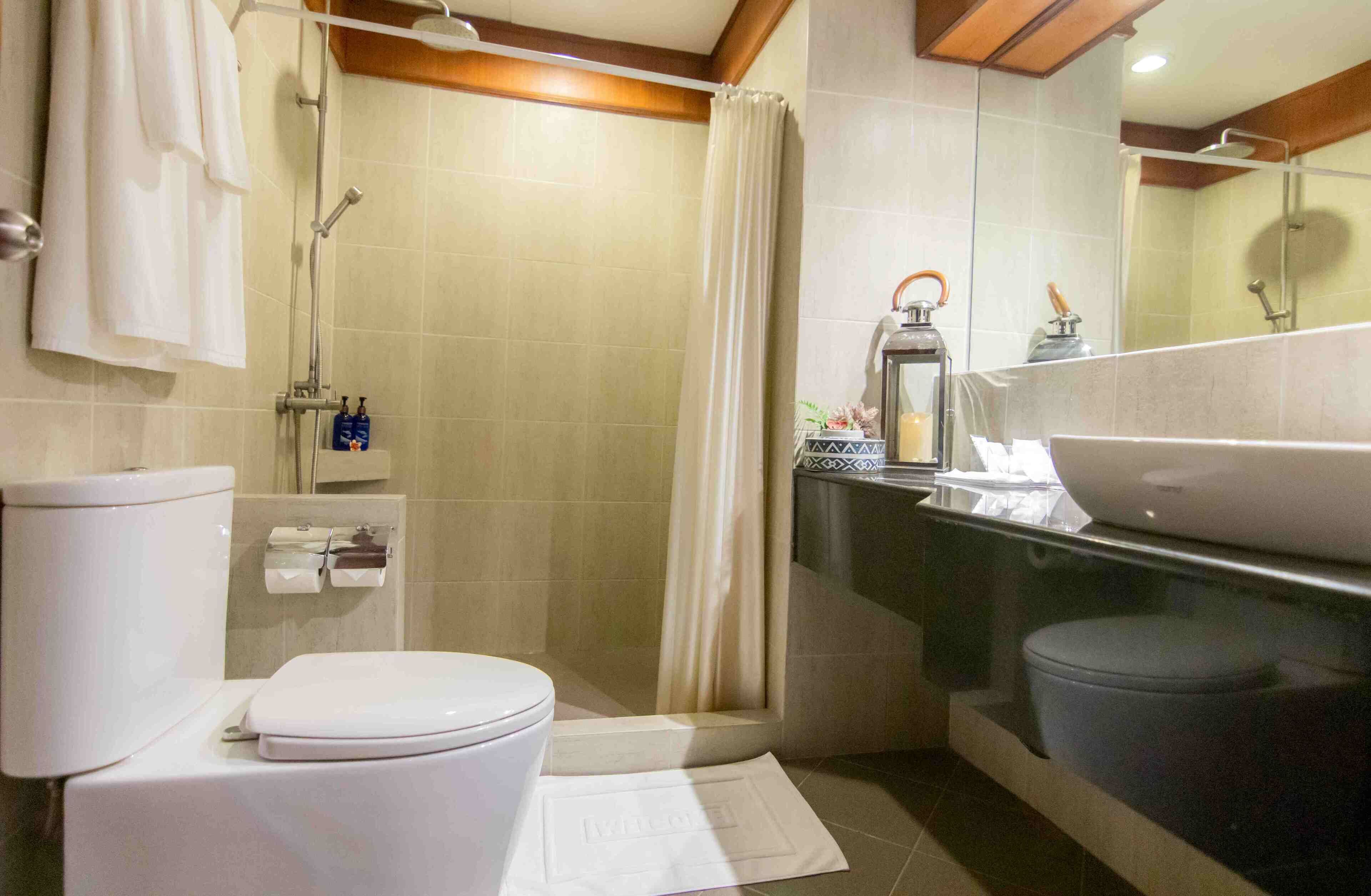 A bathroom with a toilet, shower, and sink.