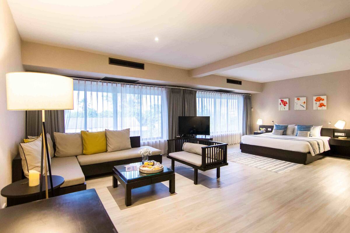 Una habitación de hotel moderna con sofá, sillón y cama.
