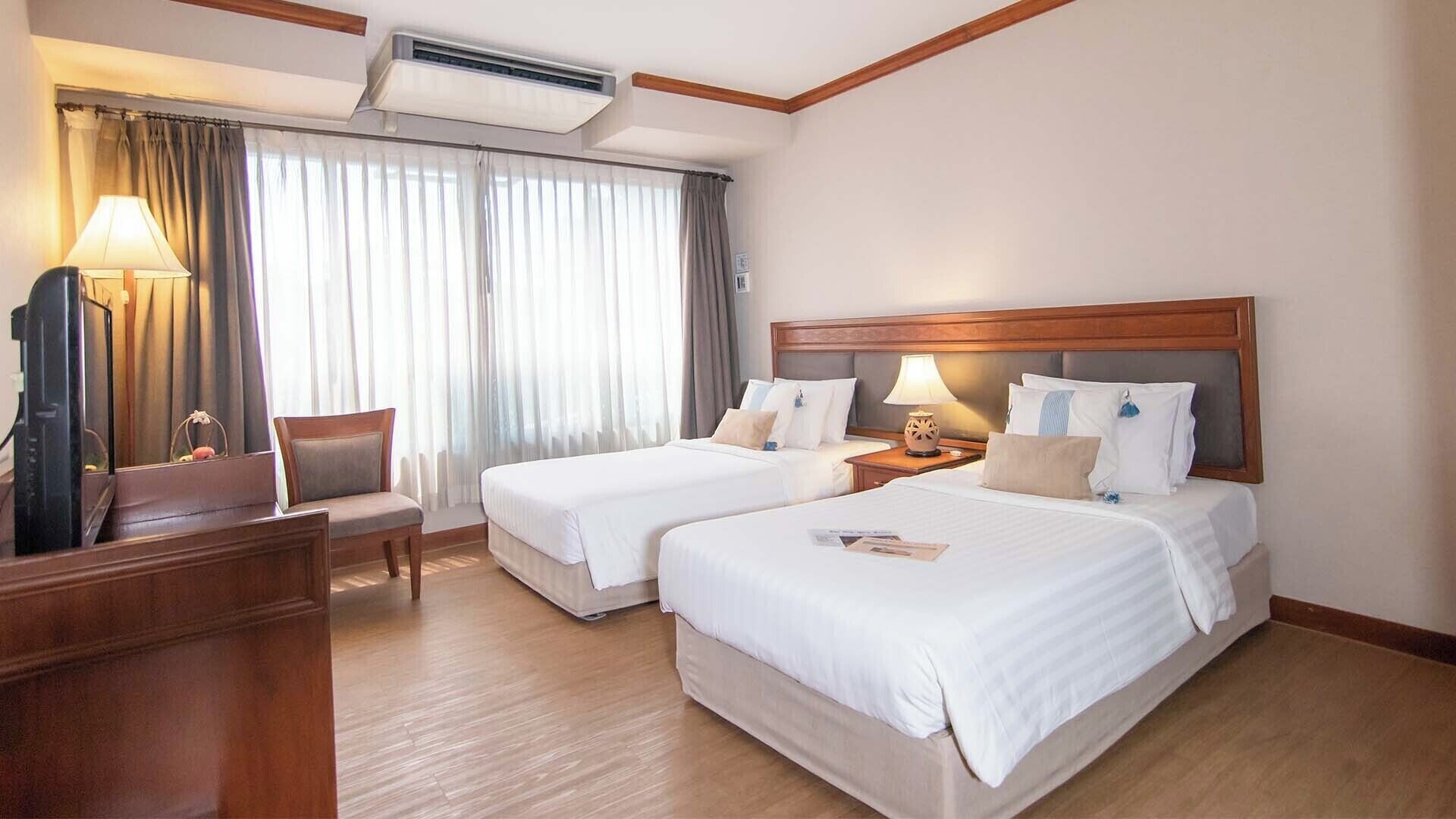 Une chambre d’hôtel avec deux lits, un bureau, une chaise et un téléviseur.