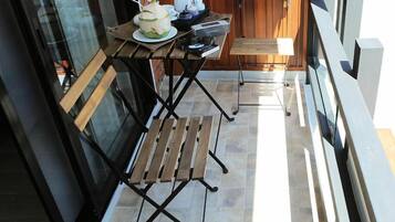 A small outdoor seating area with a wooden bench and a table, a coconut drink, and a laptop.