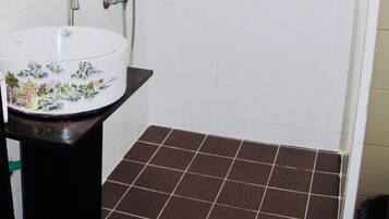 Une salle de bain avec un lavabo blanc, un miroir et une douche.