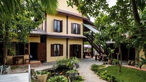 A two-story building with a garden courtyard, a small pond, and a staircase leading to a covered area. - Villa Khoum Xieng Thong Boutique (Luang Prabang)