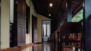 A hallway with wooden flooring, a ceiling with exposed beams, and a door with a curtain. - Villa Khoum Xieng Thong Boutique (Luang Prabang)