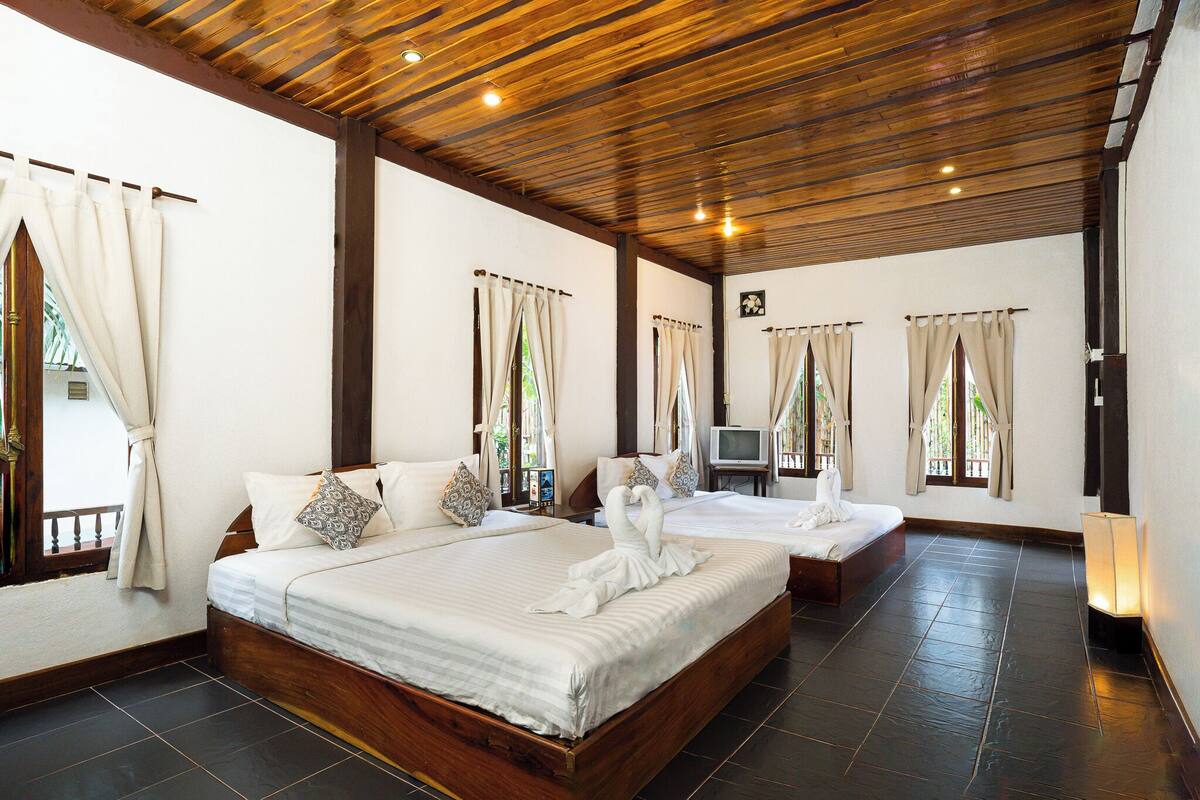 A hotel room with a large bed, a smaller bed, and a TV.