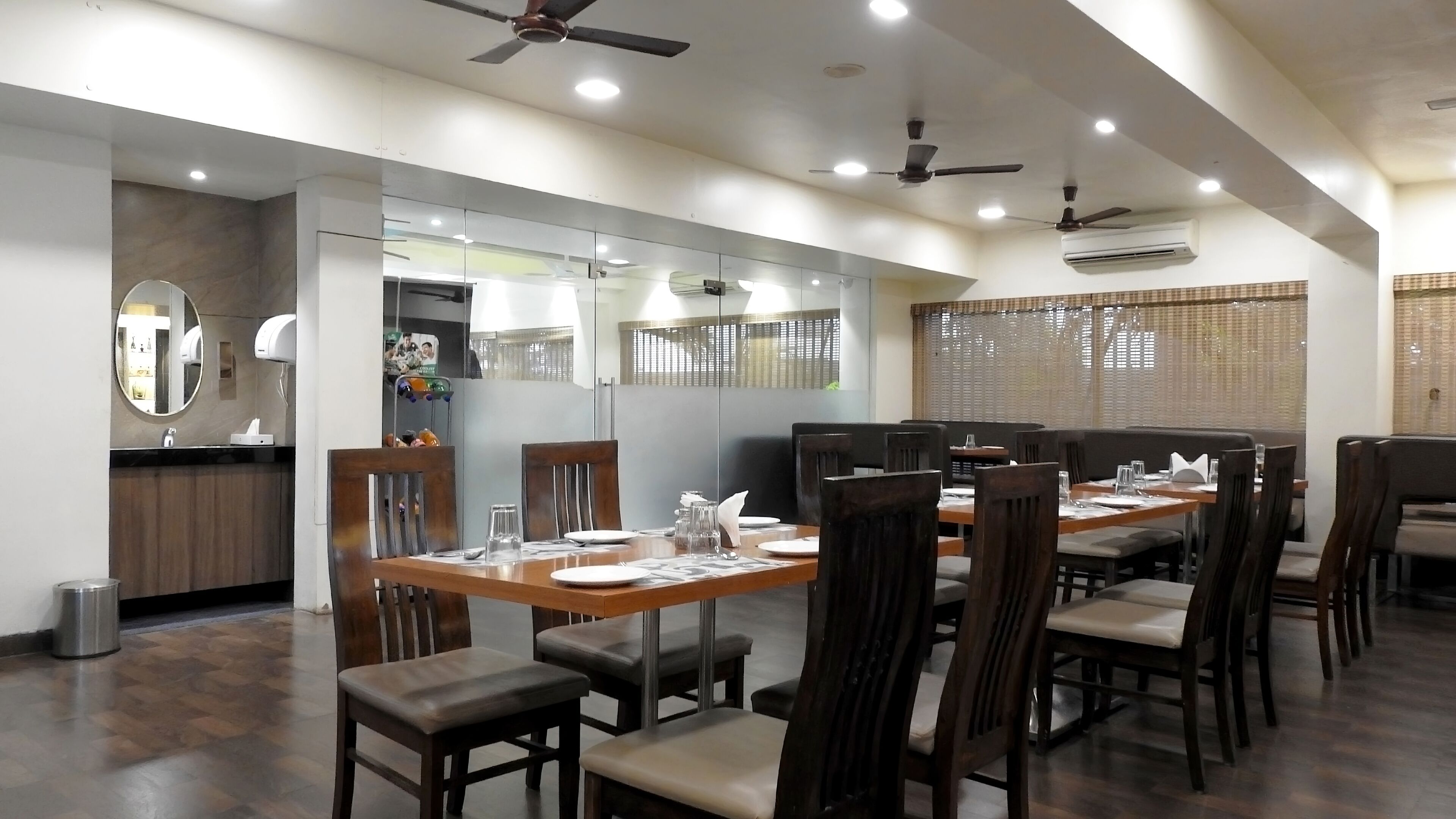 A dining area with wooden tables and chairs, ceiling fans, and an air conditioning unit.