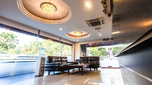A modern lobby with a chandelier, leather seating, and large windows overlooking greenery. - Lavender Inn Nusa Bestari (Johor Bahru)