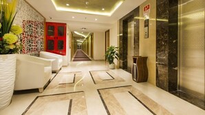 Un moderno vestíbulo de hotel con piso de mármol, una puerta roja y un mostrador de recepción.