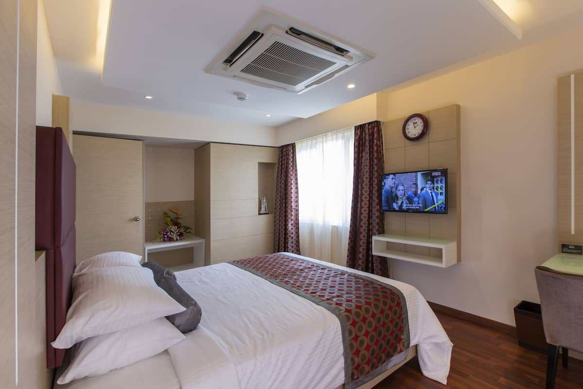Ein Hotelzimmer mit Bett, Fernseher, Uhr und Spiegel.