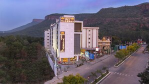Un hotel moderno con un cartel llamativo, situado en una esquina con vistas a la montaña.