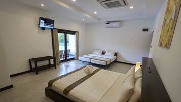 Habitación de hotel con una cama grande, una cama más pequeña, televisión, equipo de aire acondicionado y puerta de vidrio corredera al exterior.