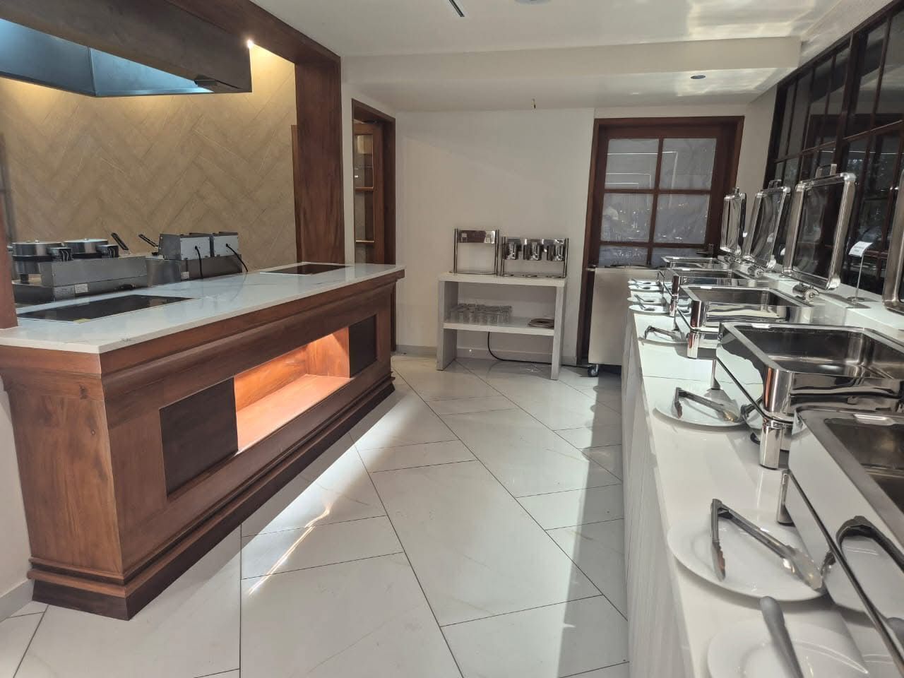 Een moderne keuken met een centraal eiland, roestvrijstalen apparatuur en een raam met uitzicht.