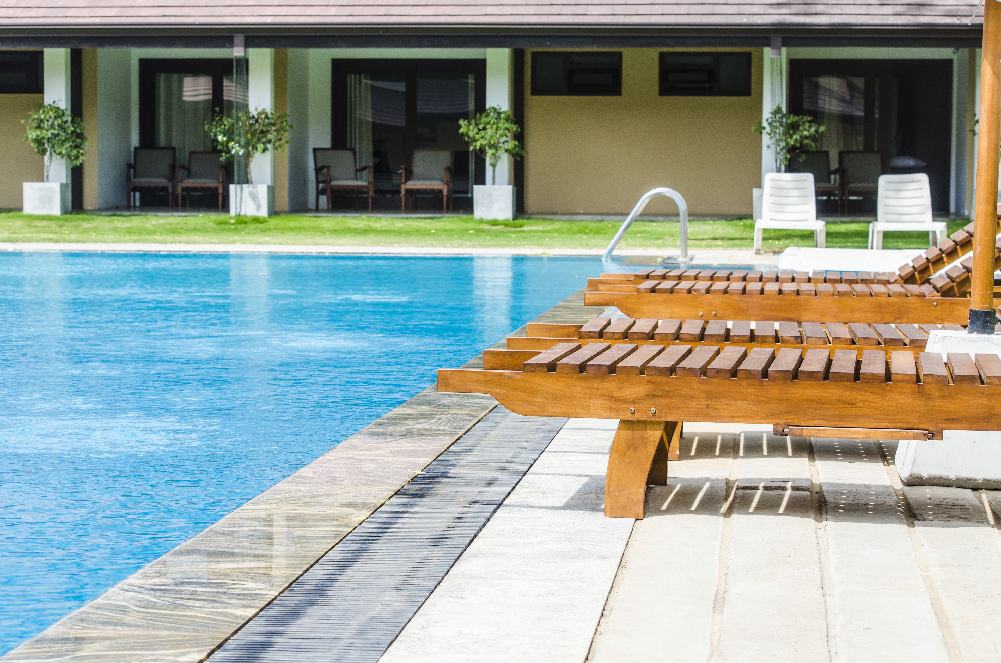 Una piscina al aire libre, sombrillas, sillones reclinables de piscina