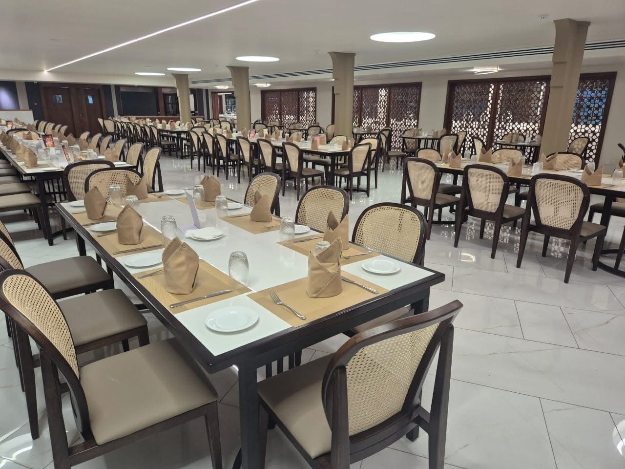 A large dining hall with long tables, chairs, and a modern ceiling design.