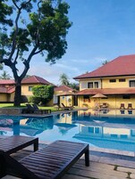 Una piscina al aire libre, sombrillas, sillones reclinables de piscina