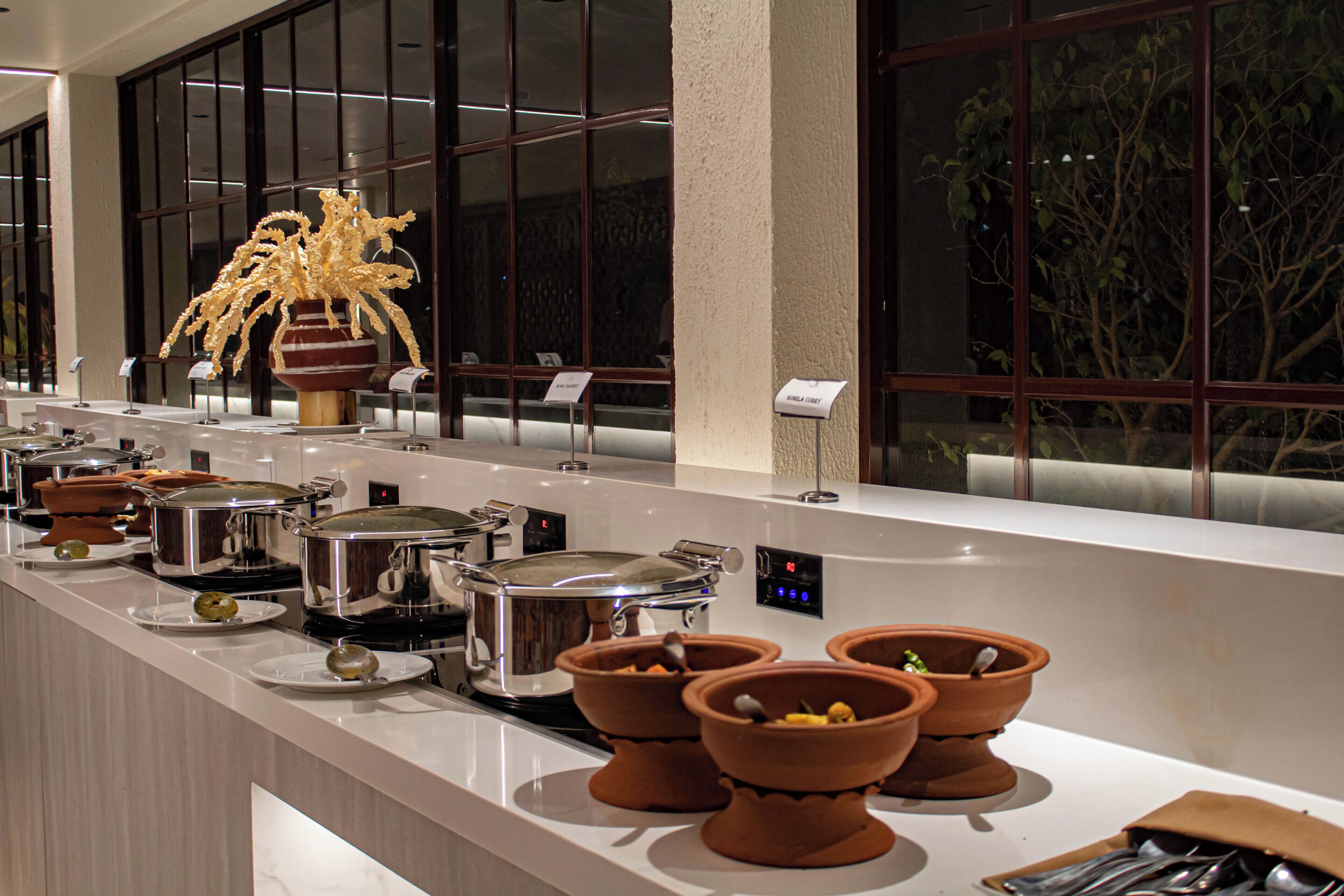 Een buffetopstelling met diverse gerechten, een decoratieve plant en uitzicht uit het raam.