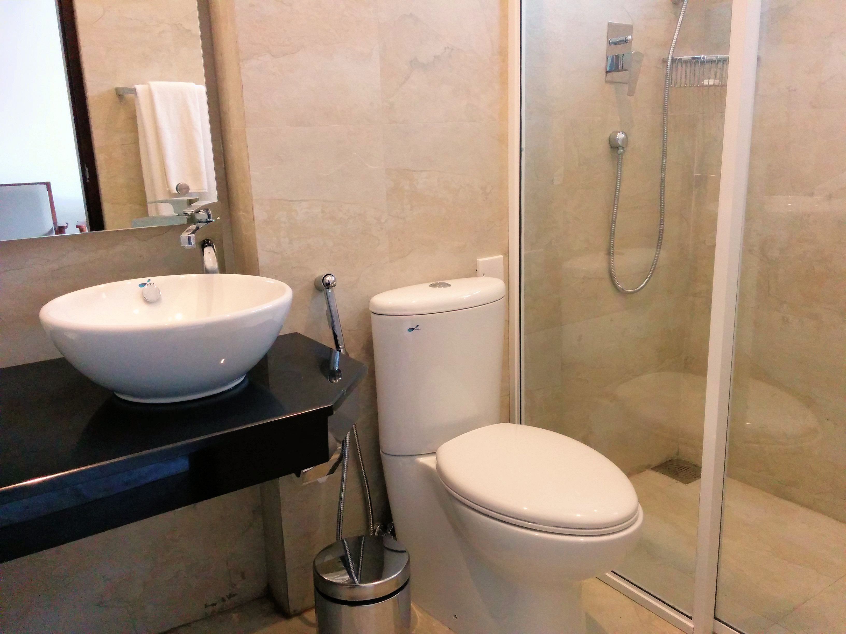 A bathroom with a white sink, toilet, and glass-enclosed shower.
