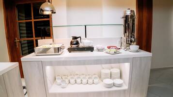 A modern breakfast bar with a coffee machine, tea set, and various dishes.