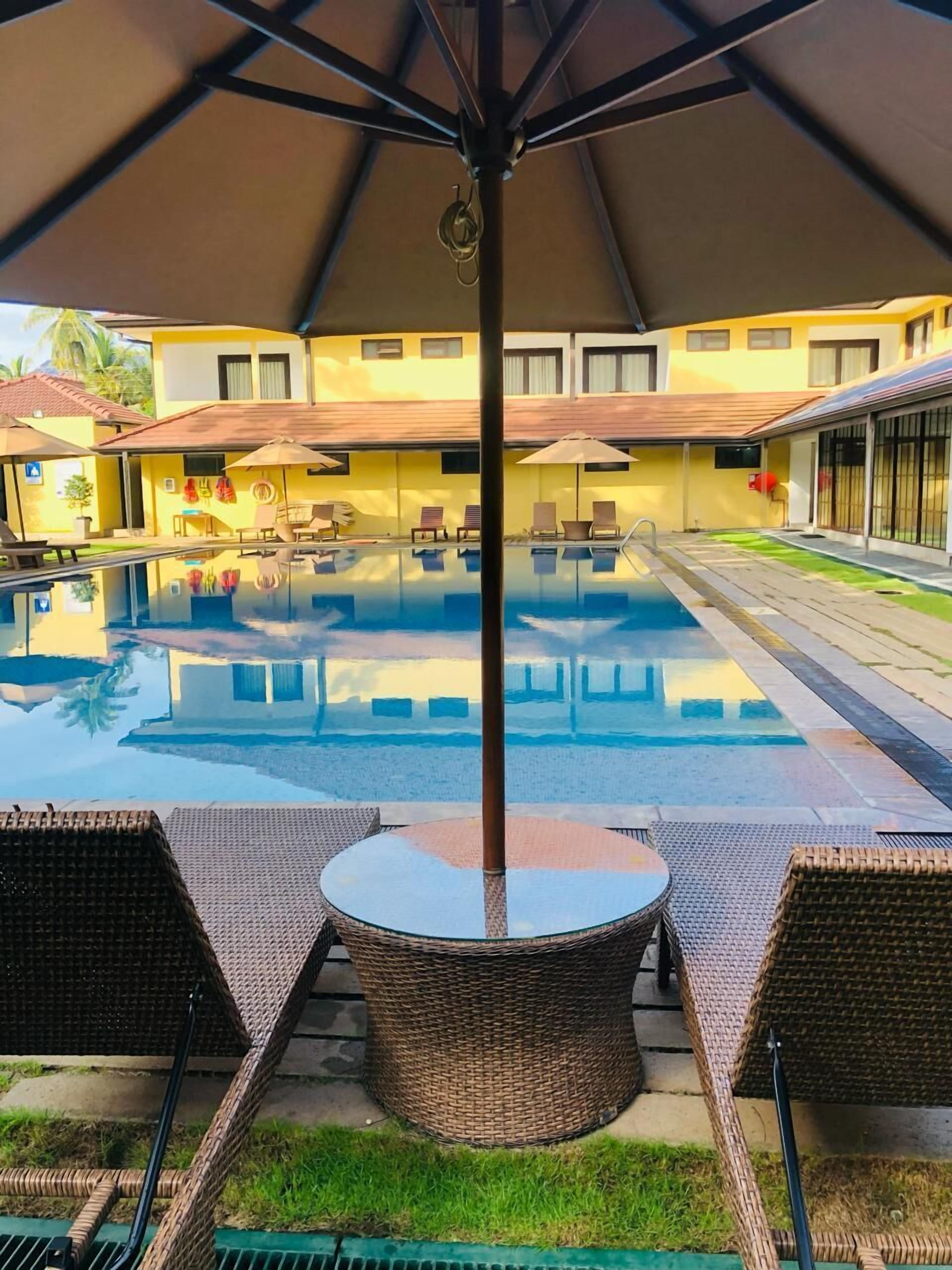En swimmingpool med solstolar och parasoller, omgiven av byggnader.