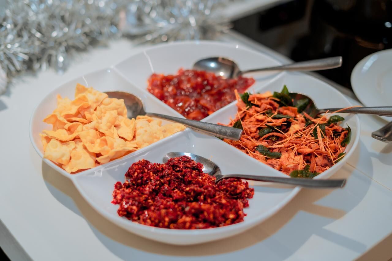A white plate with four different food items, each with a spoon.