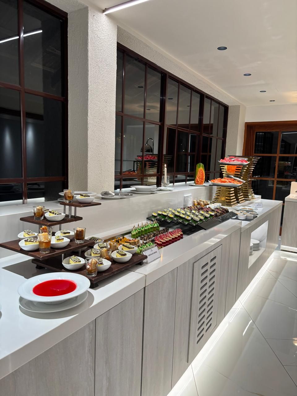 Disposição de buffet com diversos alimentos e um arranjo de velas.